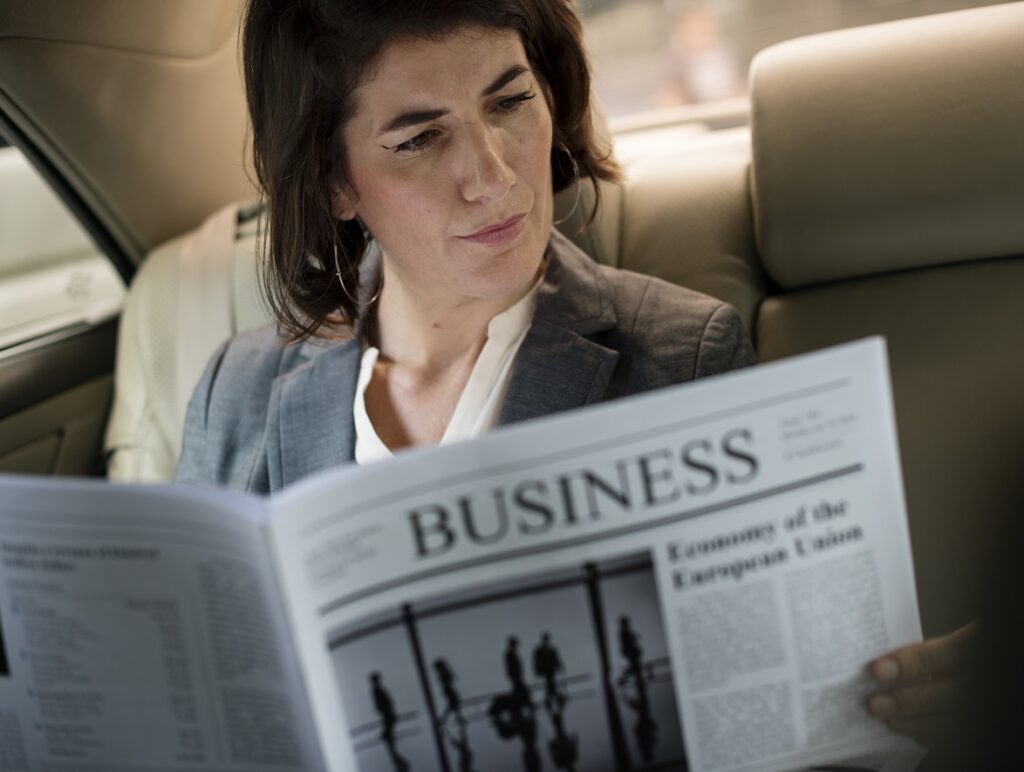 4 Reasons to Take a Limo to Airport Instead of a Bus - businesswoman reading newspaper car inside 2022 12 16 00 36 04 utc , limo to airport